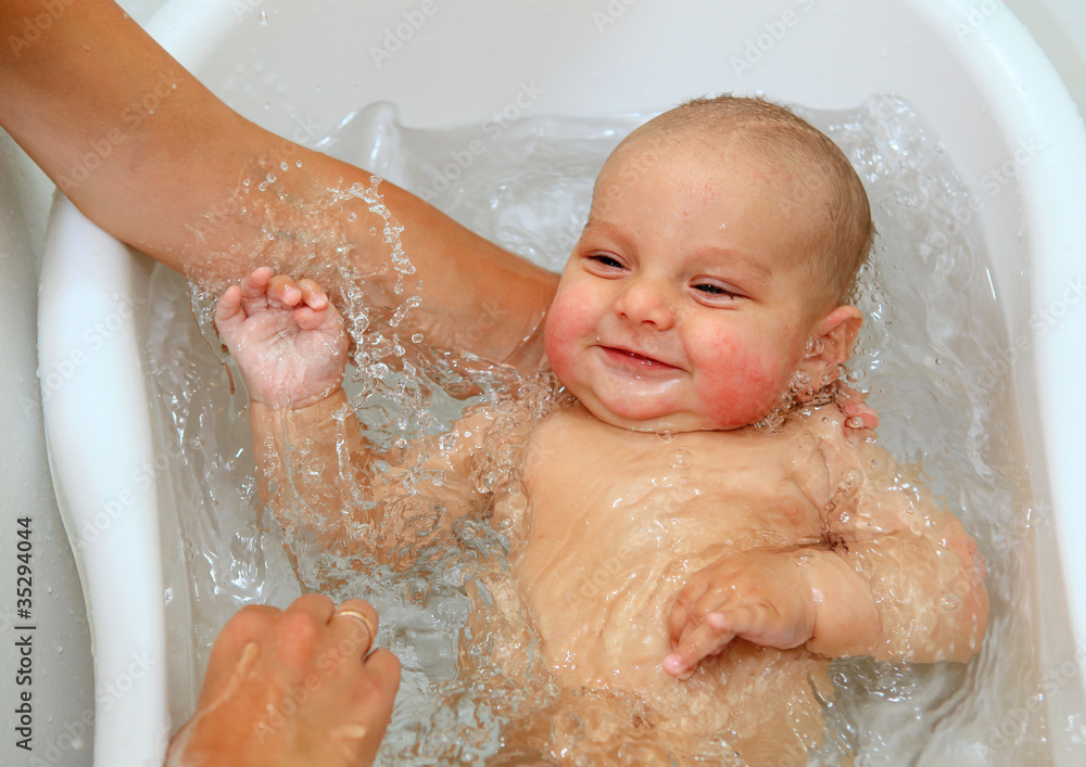 Cute baby boy enjoying bath, laughing while splashing water Cute baby boy enjoying bath, laughing while splashing water