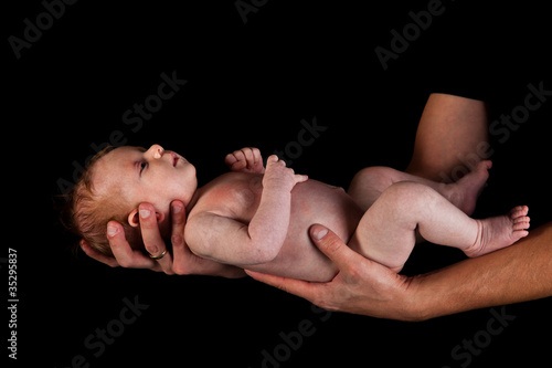 Infant girl on fathers arms isolated on black