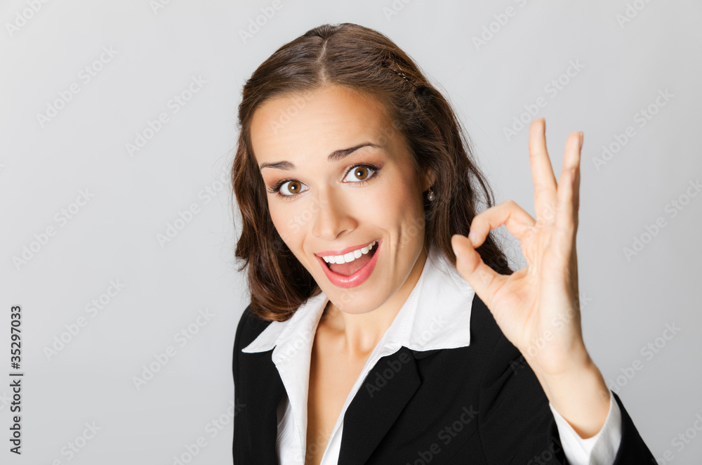 Happy business woman with okay gesture, over grey Happy business woman with okay gesture, over grey