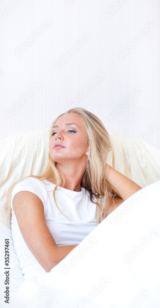 Young blond woman enjoying a sunny morning in bed. Vertical Shot Young blond woman enjoying a sunny morning in bed. Vertical Shot