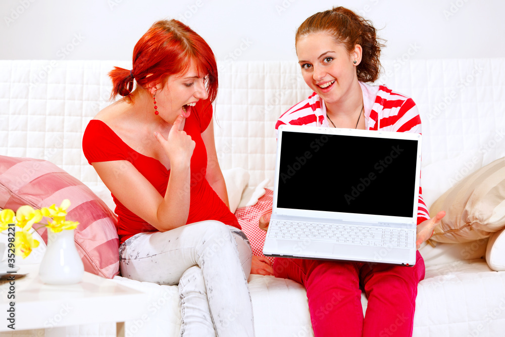 Two cheerful girlfriends showing laptops blank screen Two cheerful girlfriends showing laptops blank screen