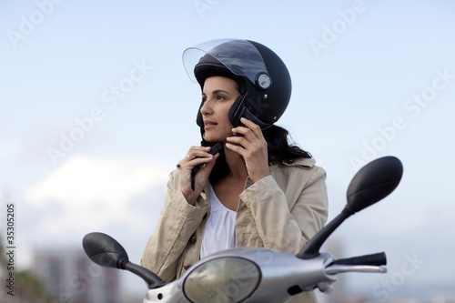 Attraktive Frau auf Roller zieht ihren Helm aus