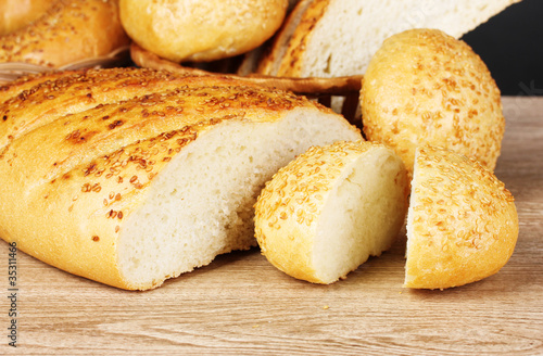 rye and white bread and buns on wooden background