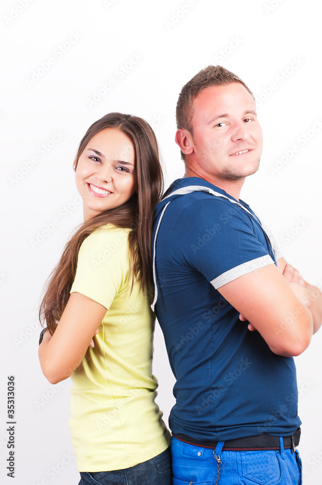 Portrait of a happy young couple standing back to back against w Portrait of a happy young couple standing back to back against w