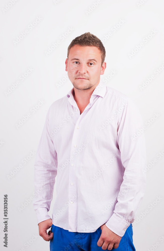 Portrait of casual young man, standing with hands in pocket, smi Portrait of casual young man, standing with hands in pocket, smi