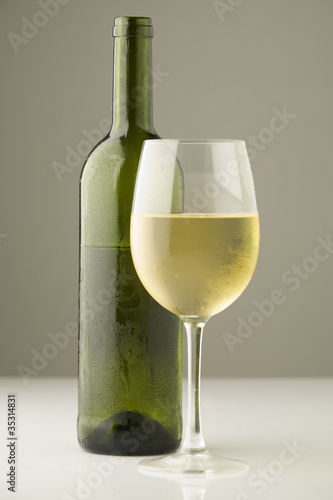Opened bottle of organic white wine and a glass