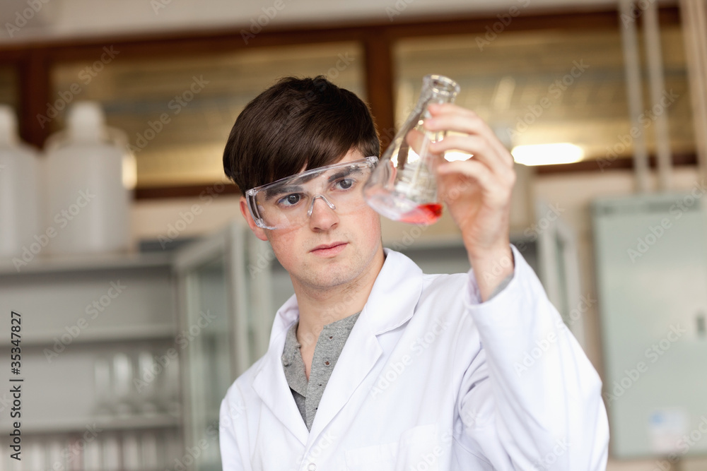 Scientist looking at a liquid in an Erlenmeyer flask Scientist looking at a liquid in an Erlenmeyer flask