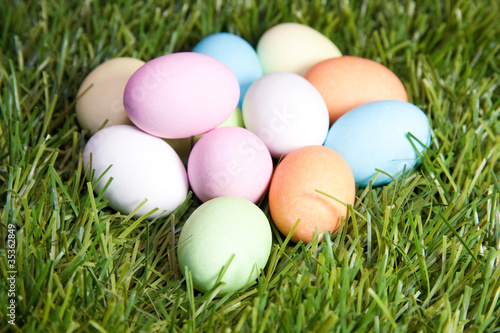 several colored easter eggs in the green grass with white, blue, pink and orange