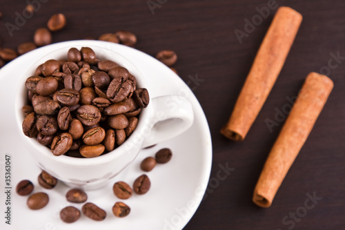 cup with coffee beans and cinnamon sticks