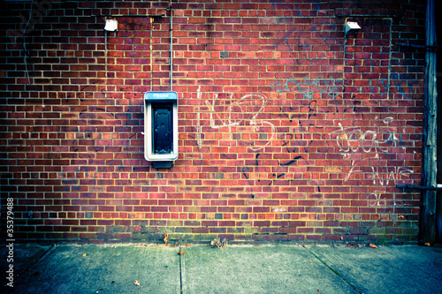 Obsolete Payphone on a Grungy Urban Brick Wall