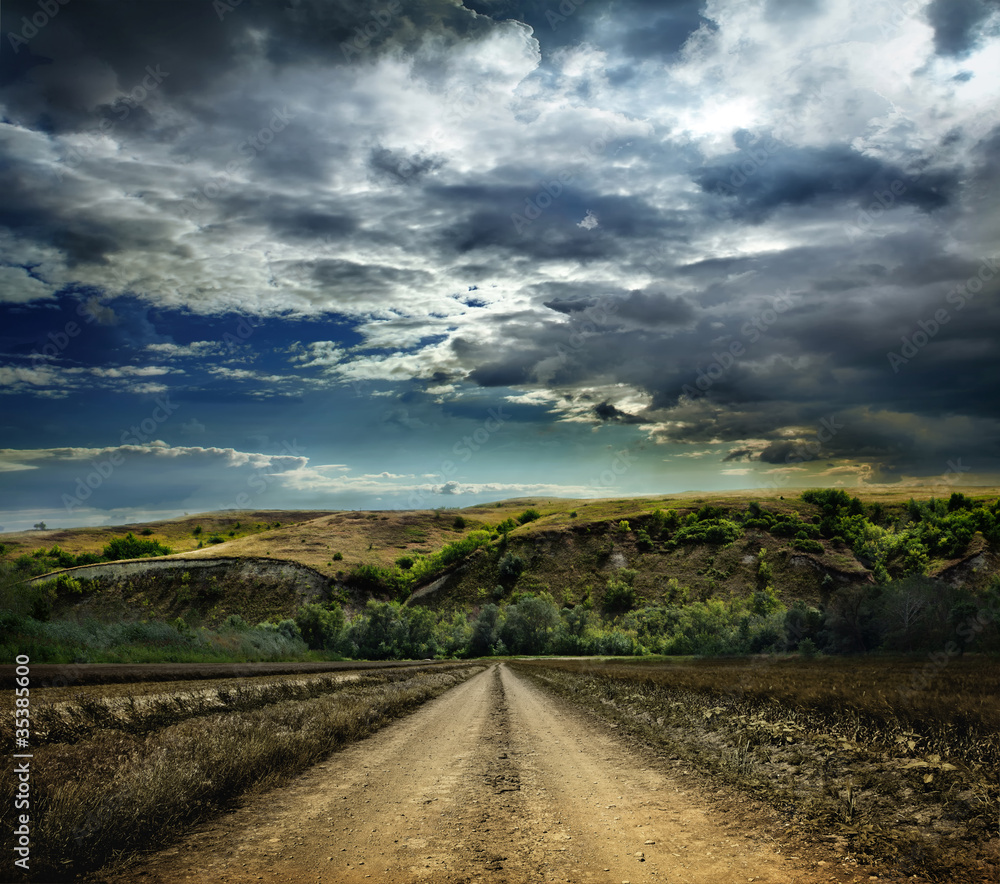 Rural road through the field in the mountains