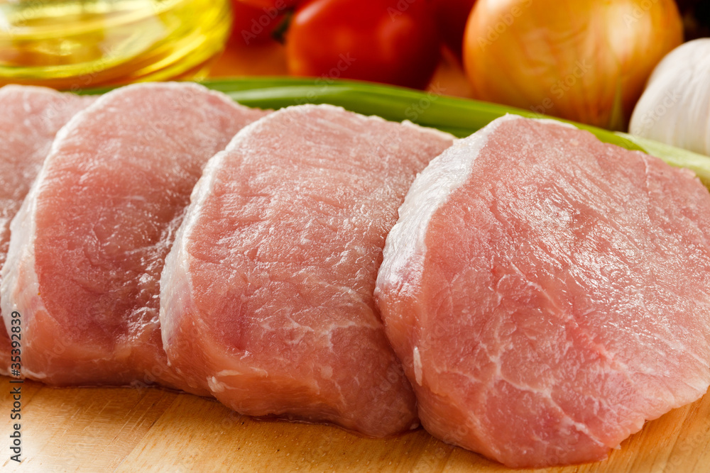 Raw pork on cutting board and vegetables Raw pork on cutting board and vegetables