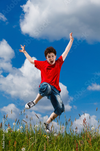 Boy jumping, running against blue sky