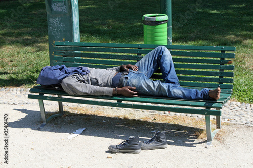 poor marginalized homeless sleeping in a outdoor bench photo