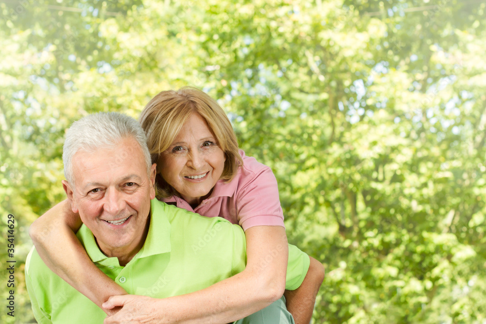 Portrait of happy senior man giving piggyback ride mature woman