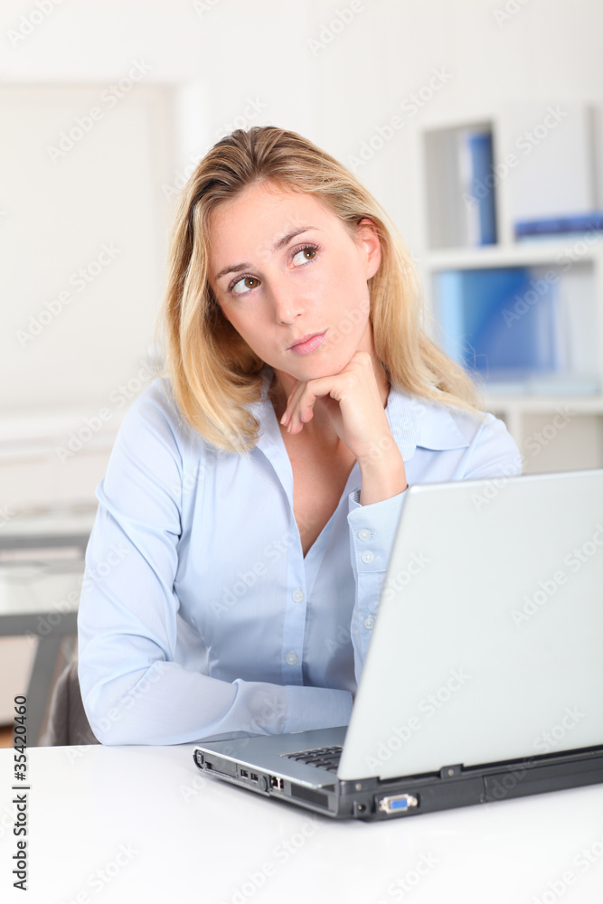 Blond woman at work with thoughtful look Blond woman at work with thoughtful look