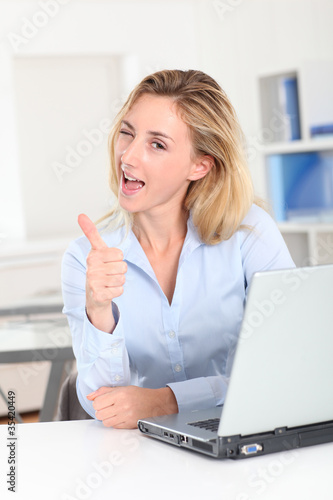 Blond woman at work showing thumb up