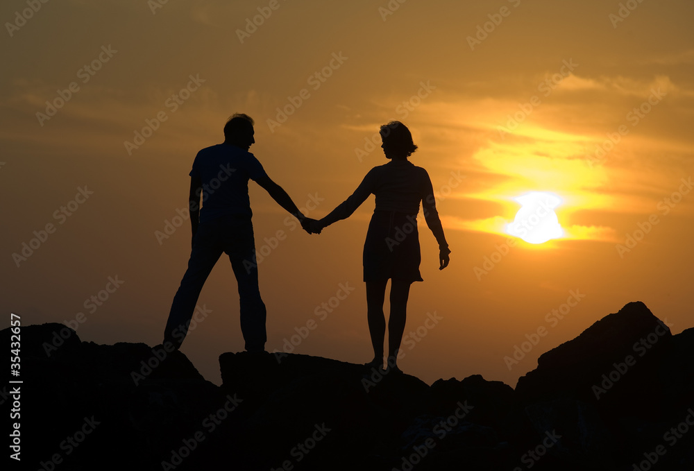 Couple on pier by sunset