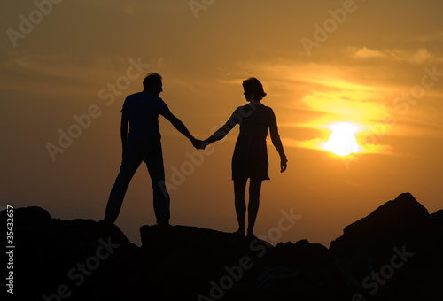 Couple on pier by sunset