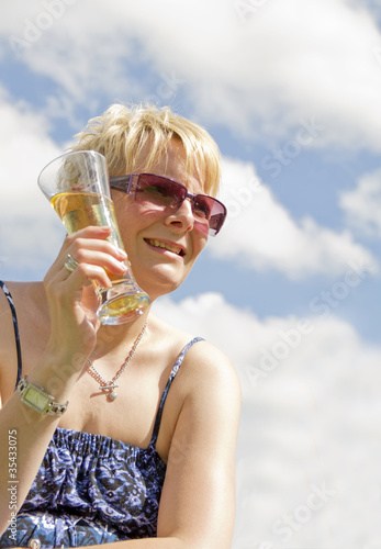 Blond women enjoying a cold glass of cider in the sun