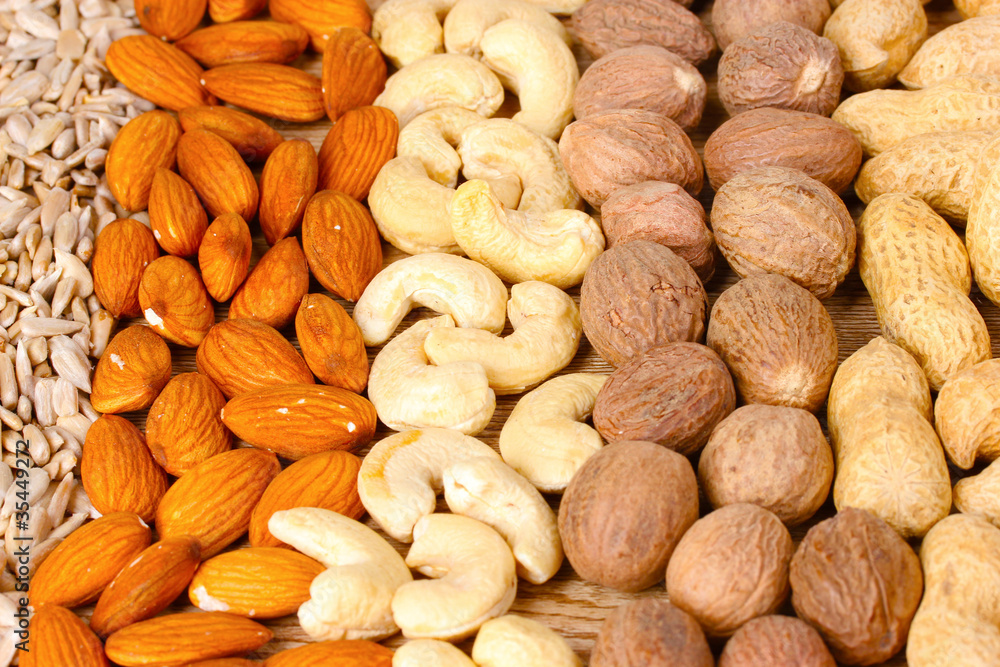 nutmeg, peanuts, hazelnuts and almonds on wooden background nutmeg, peanuts, hazelnuts and almonds on wooden background
