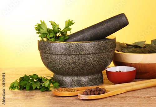 Mortar and pestle, bowls, parsley and pepper on yellow backgroun