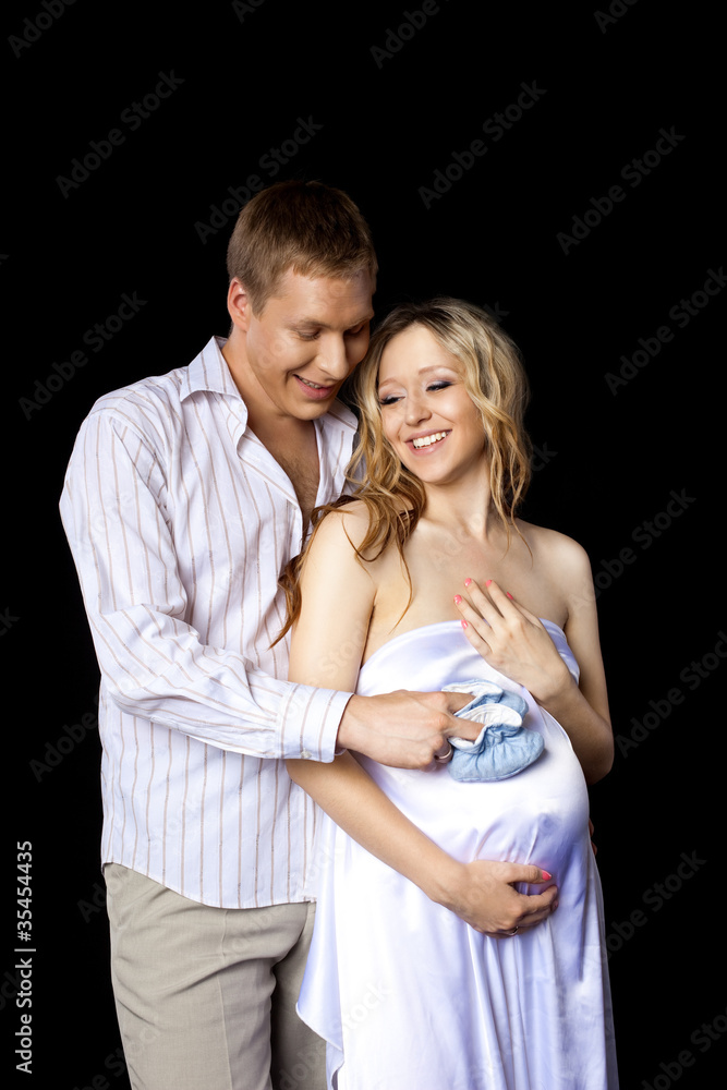 Young couple wait for baby with baby's bootee Young couple wait for baby with baby's bootee