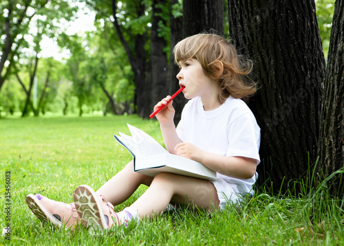 Portrait of little girl reading a book in the park