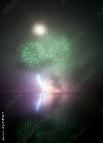 Colorful fireworks on black sky background with water reflection