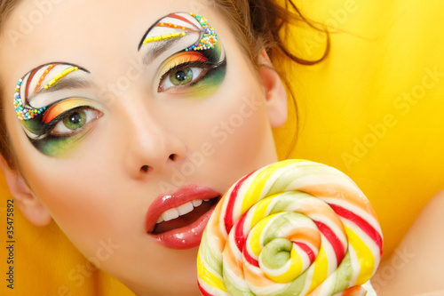 woman licks candy with beautiful make-up photo