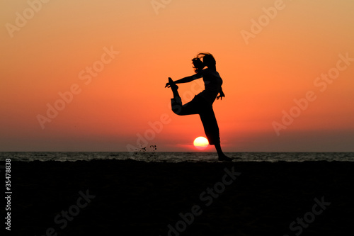 silhouette of female dancer in sunset at beach