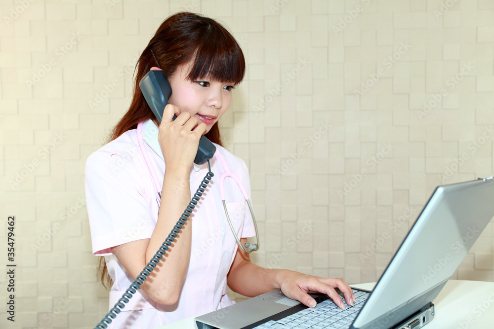 電話対応をしながらデータの確認をする看護師
