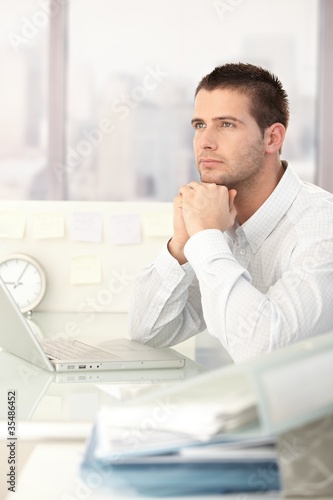 Daydreaming businessman sitting at desk