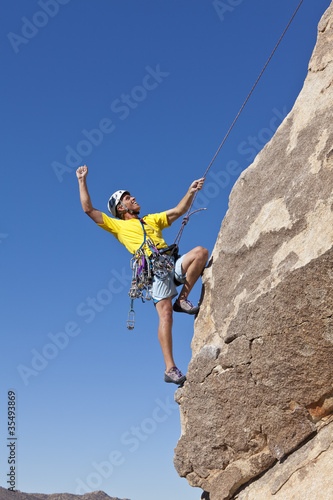 Male rock climber clings to a cliff.