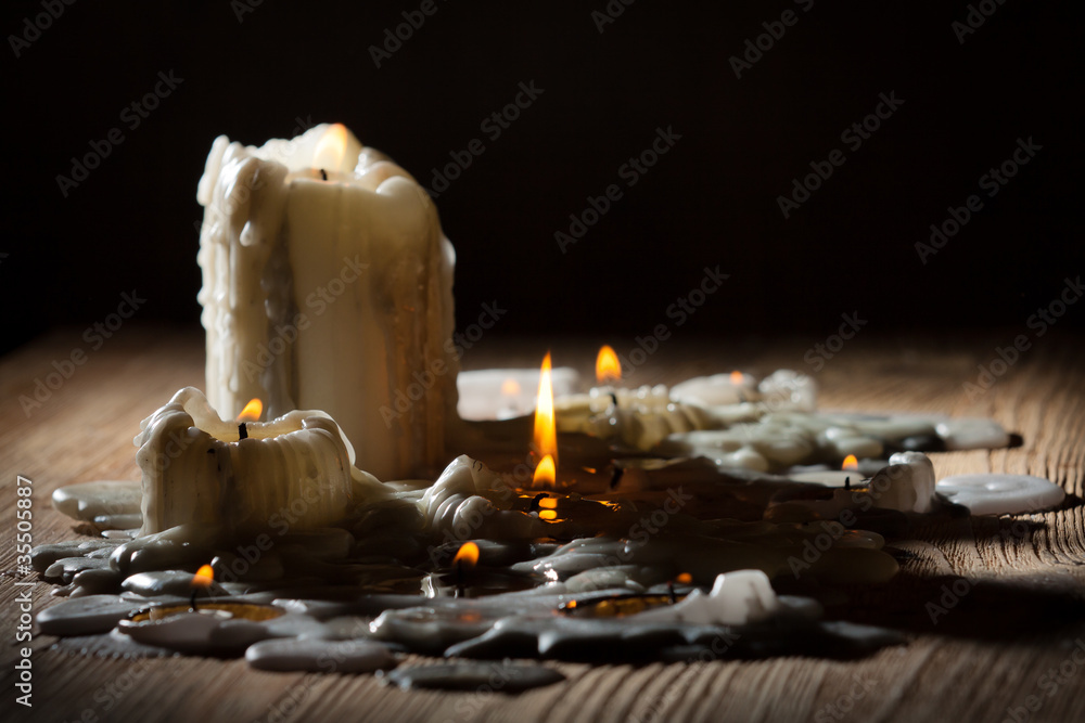 Obraz premium Melting candls with fire on wooden shelf