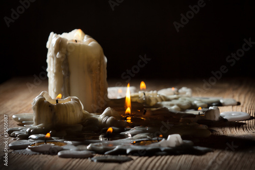 Melting candls with fire on wooden shelf photo