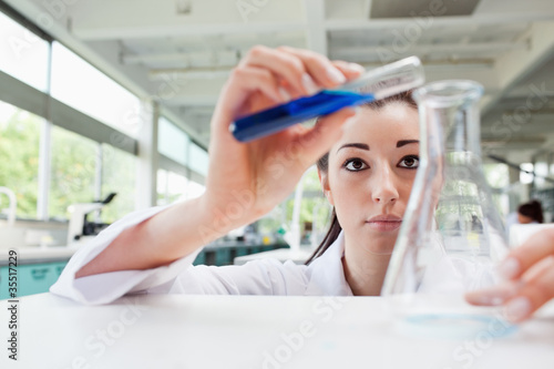 Focused science student pouring liquid