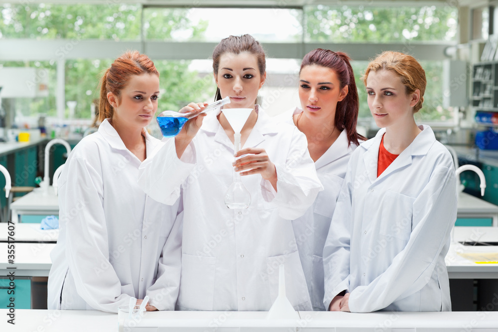 Science students pouring liquid in a flask Science students pouring liquid in a flask