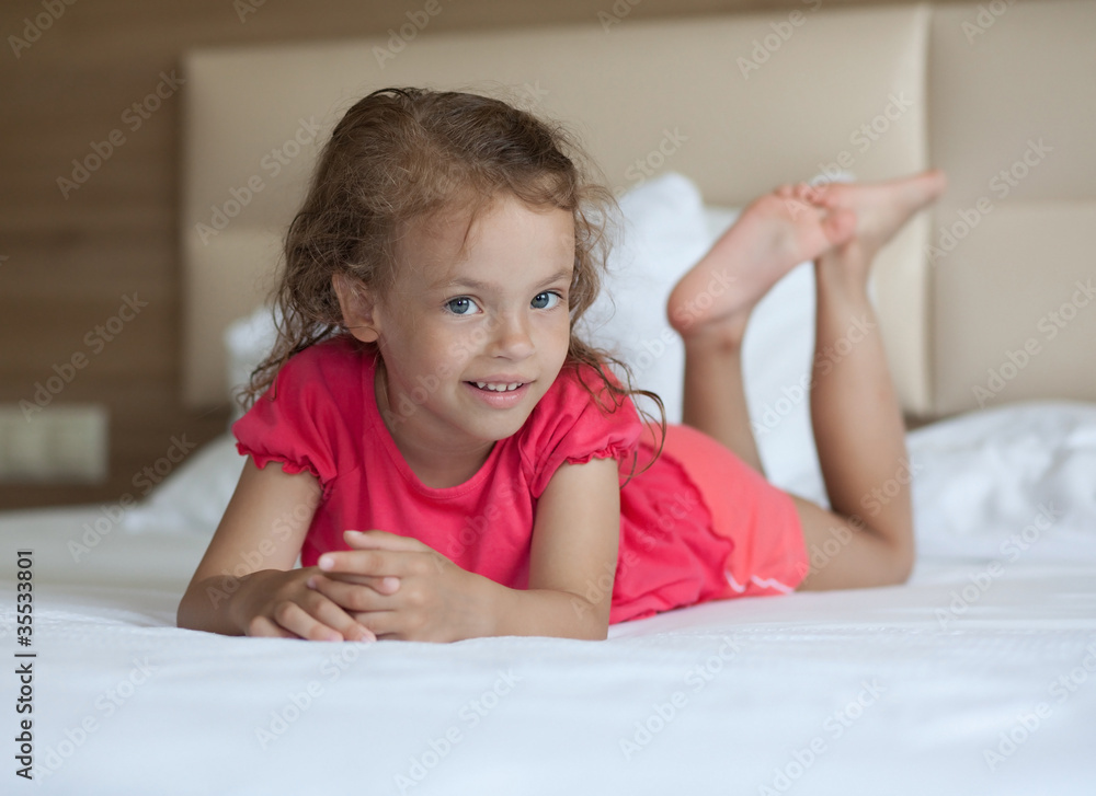 Cheerful little girl lying on the bed. Cheerful little girl lying on the bed.