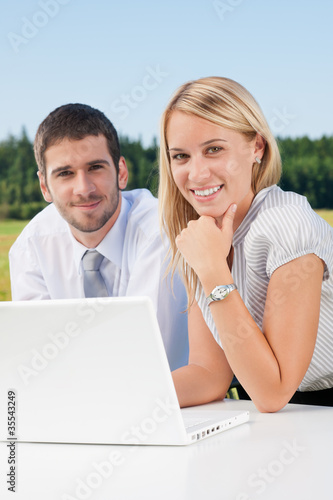 Business colleagues in nature with laptop smile