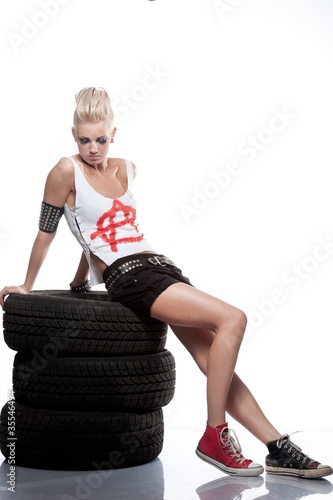 Punk girl sitting on a tires. photo