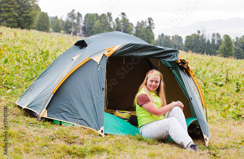 girl has a rest in green tent against mountains