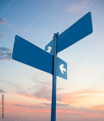 Blank white road signs in dusk sky.