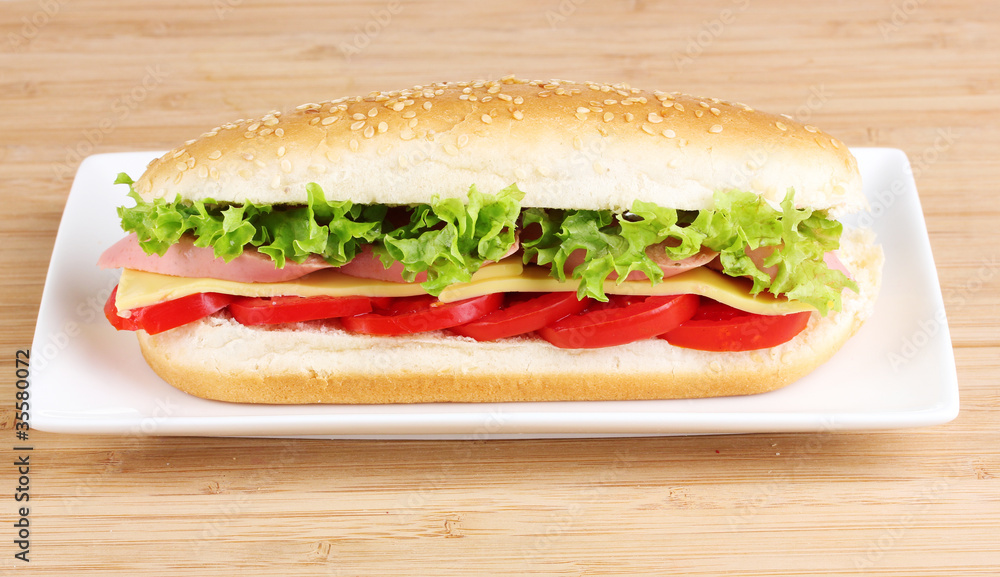 Sandwich with sausage, cheese and tomatoes on plate on wooden ba Sandwich with sausage, cheese and tomatoes on plate on wooden ba