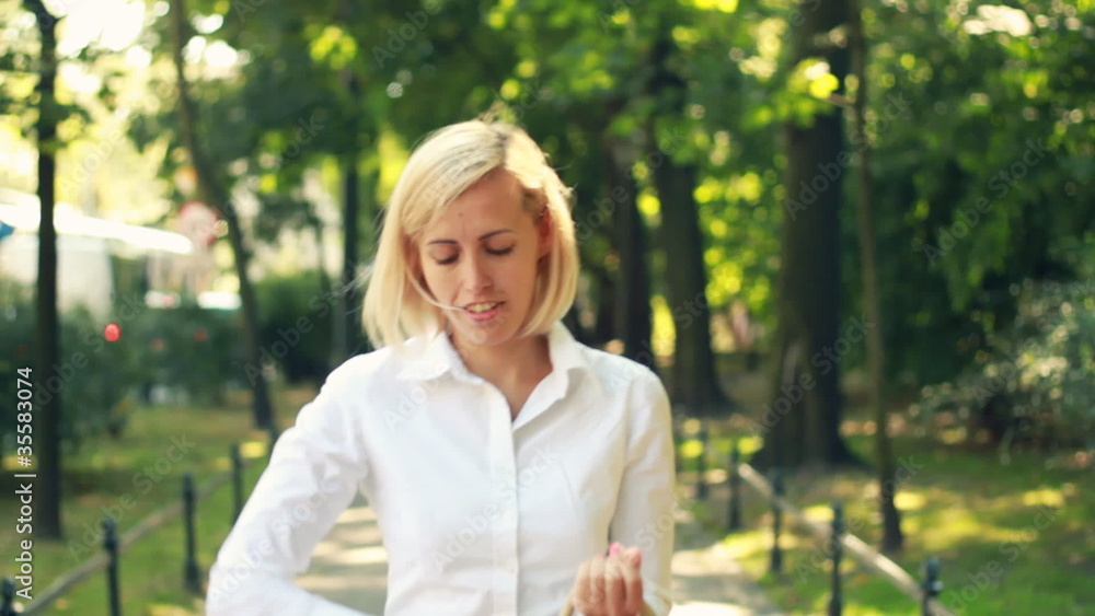 Businesswoman walking and talking on cellphone in the city park Businesswoman walking and talking on cellphone in the city park