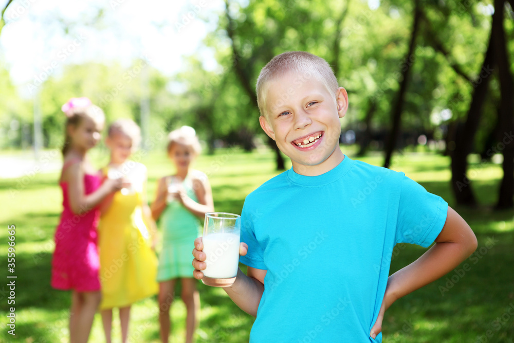 Boy drinking milk in the summer park Boy drinking milk in the summer park