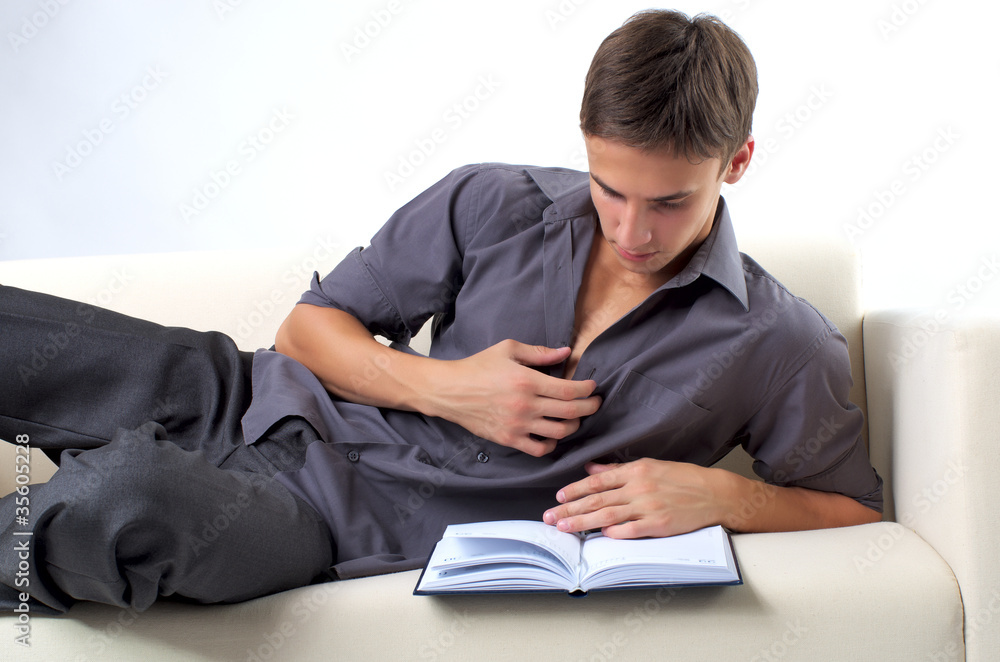 Young man reading book on the sofa at home