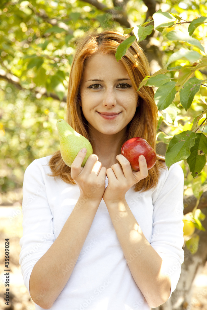 Beautiful young redhead woman standing near the apple tree. Beautiful young redhead woman standing near the apple tree.