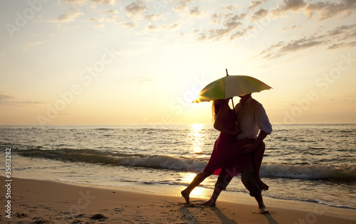 Couple kissing at the beach in sunset.