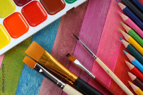 watercolor paints with brushes and colorful pencils photo